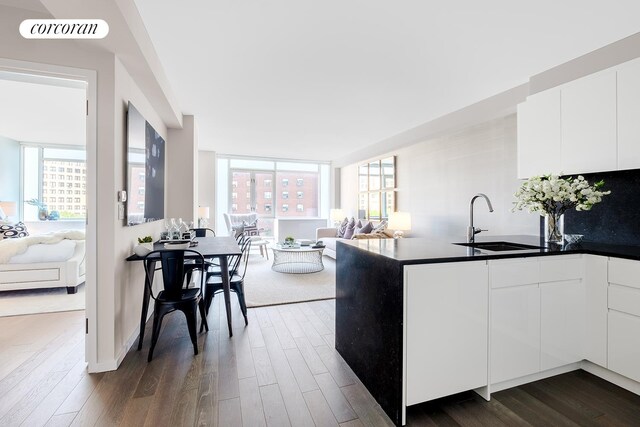 kitchen with a peninsula, a sink, visible vents, open floor plan, and dark wood-style floors