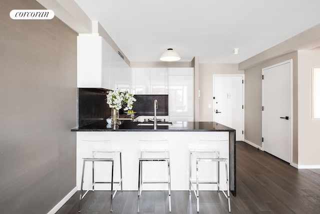 kitchen featuring a peninsula, dark countertops, dark wood-style floors, and white cabinetry