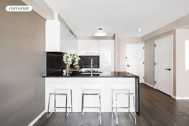 385 1st Ave Unit 8F, New York City, NY 10010 - kitchen with a peninsula, dark countertops, white cabinetry, and dark wood-type flooring