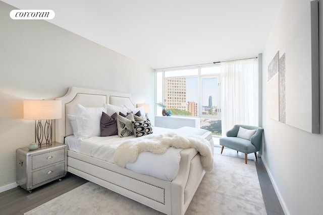 bedroom featuring a city view, wood finished floors, visible vents, and baseboards