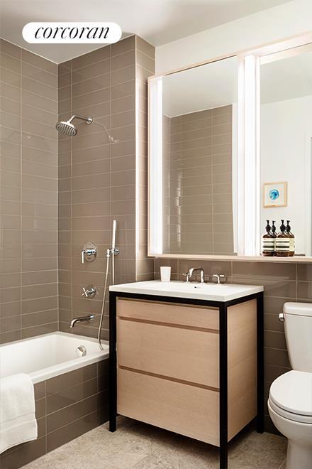 bathroom with toilet, tile patterned floors, tiled shower / bath combo, vanity, and tile walls