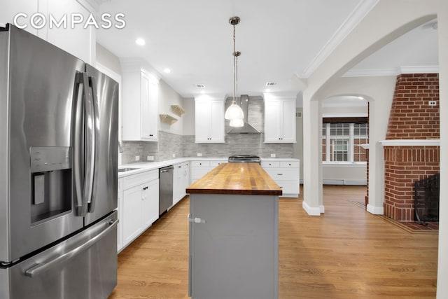 kitchen with stainless steel appliances, light wood-style flooring, butcher block counters, and wall chimney range hood