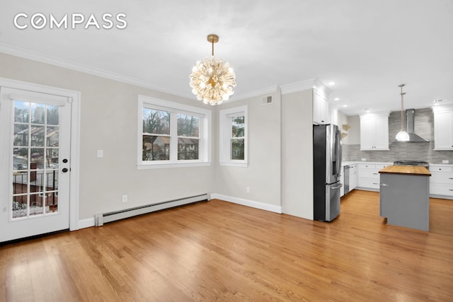 kitchen with visible vents, wall chimney range hood, baseboard heating, freestanding refrigerator, and wood counters