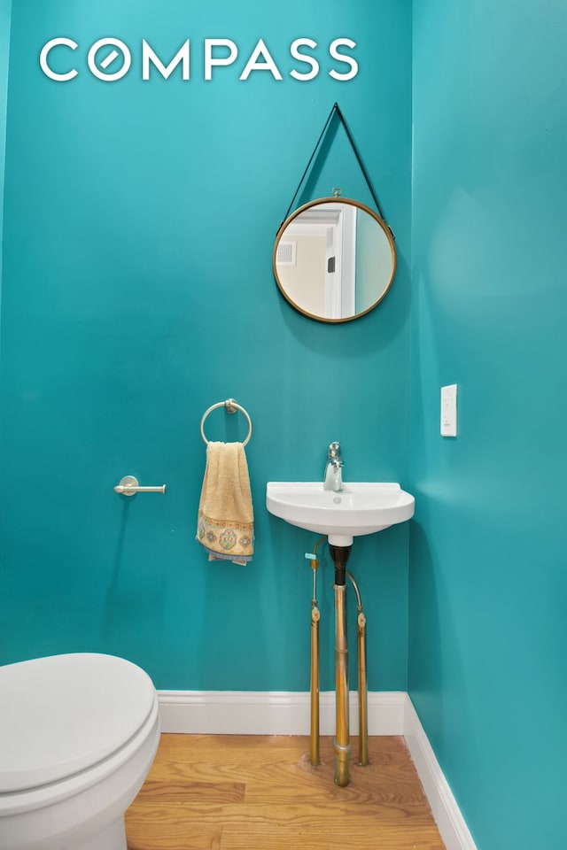 bathroom featuring toilet, baseboards, and wood finished floors