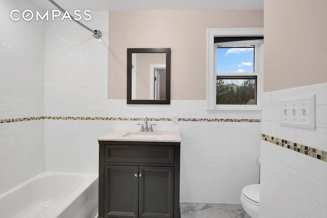 bathroom featuring toilet, vanity, shower / tub combination, marble finish floor, and tile walls