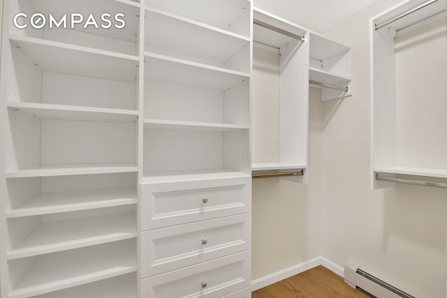 spacious closet featuring light wood-style flooring and a baseboard radiator