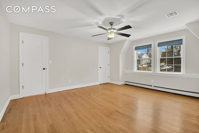 spare room featuring visible vents, light wood-style flooring, baseboards, baseboard heating, and ceiling fan