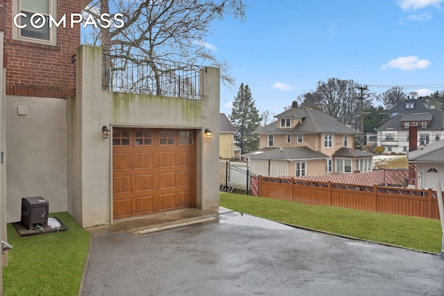 garage with a residential view, driveway, and fence