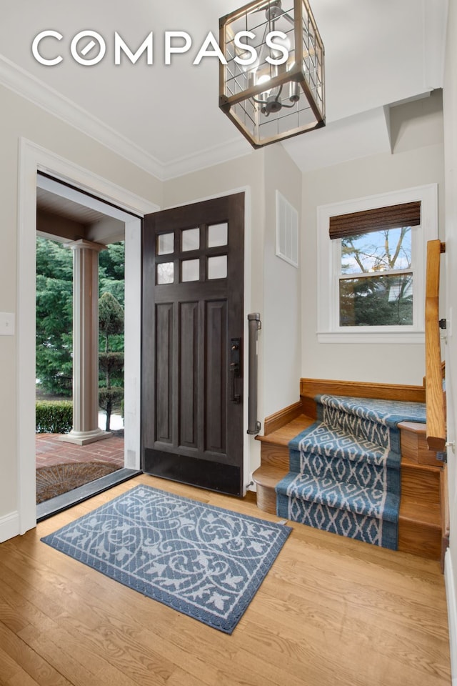 entrance foyer featuring crown molding, wood finished floors, visible vents, and baseboards