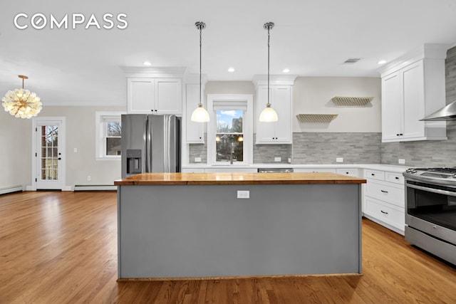 kitchen featuring a baseboard radiator, visible vents, stainless steel appliances, and butcher block countertops