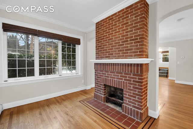 unfurnished living room featuring crown molding, a brick fireplace, and wood finished floors