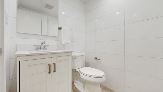 bathroom with visible vents, toilet, tile walls, and vanity