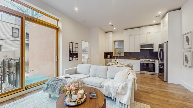 living room featuring recessed lighting, visible vents, and light wood finished floors