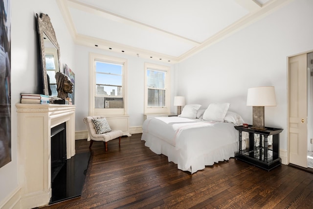 bedroom with cooling unit, dark wood-style flooring, a fireplace with raised hearth, and baseboards