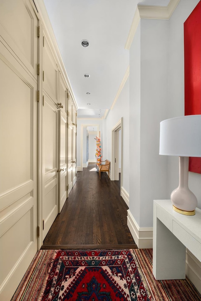 corridor featuring ornamental molding, dark wood finished floors, and baseboards