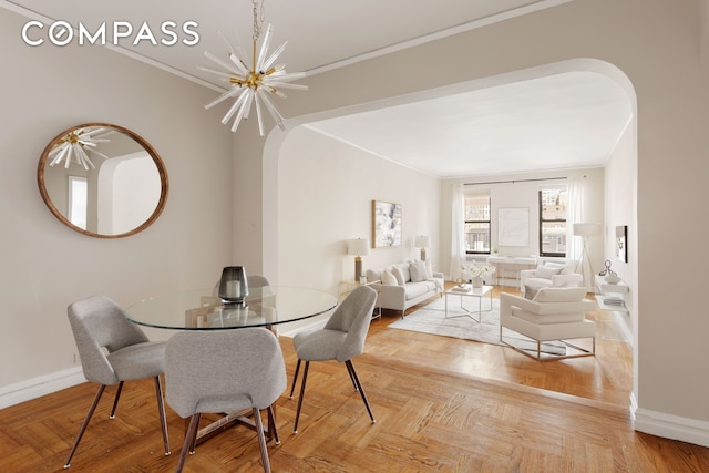 dining room with baseboards, arched walkways, a notable chandelier, and crown molding