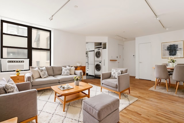 living area featuring track lighting, light wood-style flooring, cooling unit, and stacked washer / drying machine