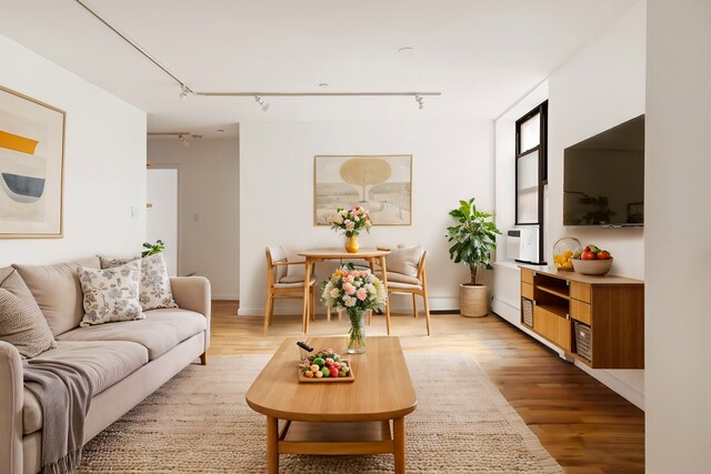 living area featuring cooling unit, stacked washer and clothes dryer, light wood-type flooring, and rail lighting