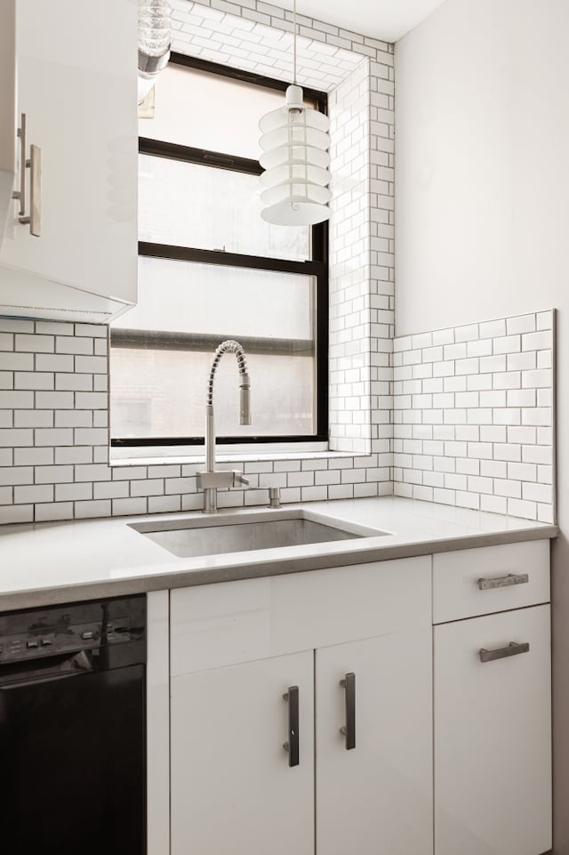 kitchen featuring backsplash, light countertops, black dishwasher, and a sink