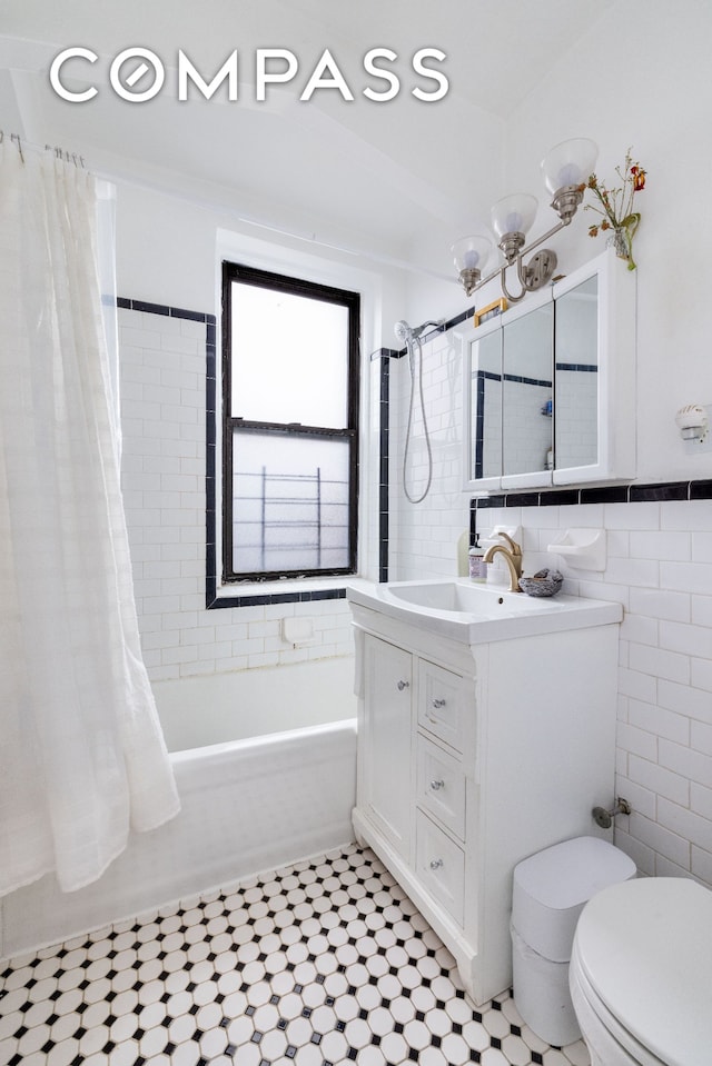 bathroom featuring toilet, shower / tub combo, vanity, and tile walls