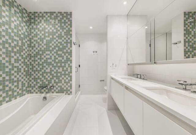 bathroom with toilet, a shower stall, tile walls, and a sink