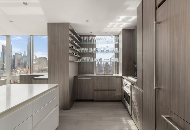 kitchen featuring a city view, open shelves, stainless steel oven, a sink, and modern cabinets