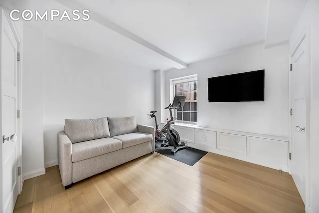 living area featuring light wood finished floors and beamed ceiling