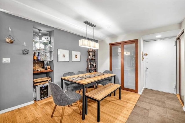 dining room with wine cooler, baseboards, and light wood finished floors