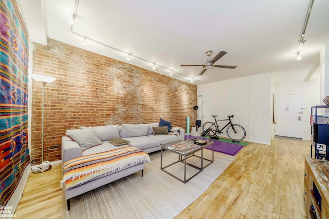 living room featuring brick wall, hardwood / wood-style floors, a ceiling fan, and track lighting