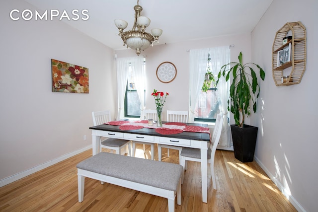 dining space featuring light wood-style floors, baseboards, and an inviting chandelier