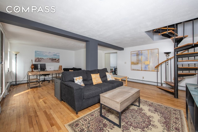 living room featuring an office area, stairs, light wood finished floors, and baseboards