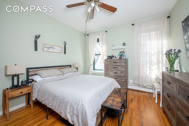 bedroom with a baseboard radiator, hardwood / wood-style flooring, and ceiling fan