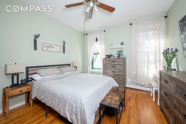 bedroom featuring a baseboard heating unit, ceiling fan, and wood-type flooring