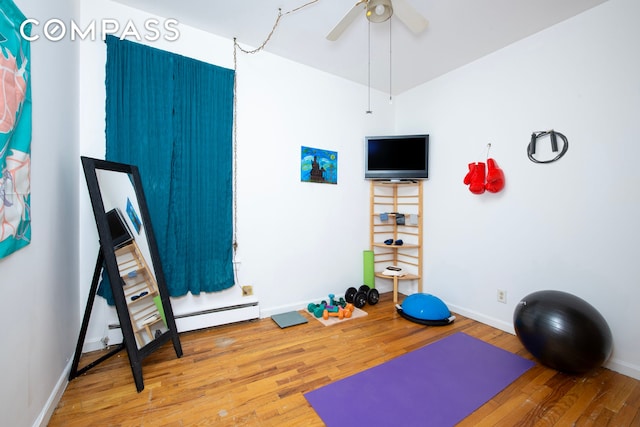 workout room with wood finished floors, baseboards, a ceiling fan, and a baseboard radiator