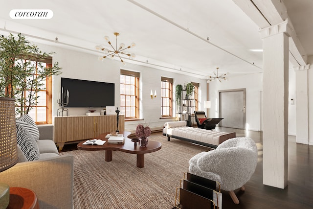 living area featuring decorative columns, visible vents, a notable chandelier, and wood finished floors