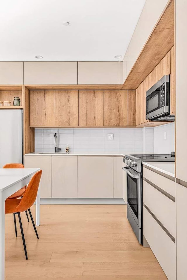 kitchen with light wood finished floors, appliances with stainless steel finishes, and modern cabinets