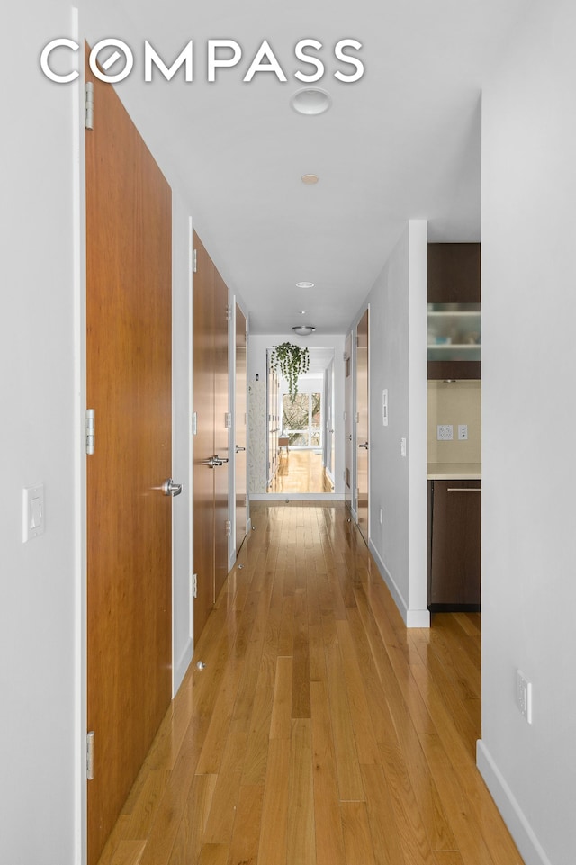 hallway featuring light wood-type flooring and baseboards