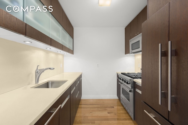 kitchen with white microwave, light countertops, high end stainless steel range oven, fridge, and a sink