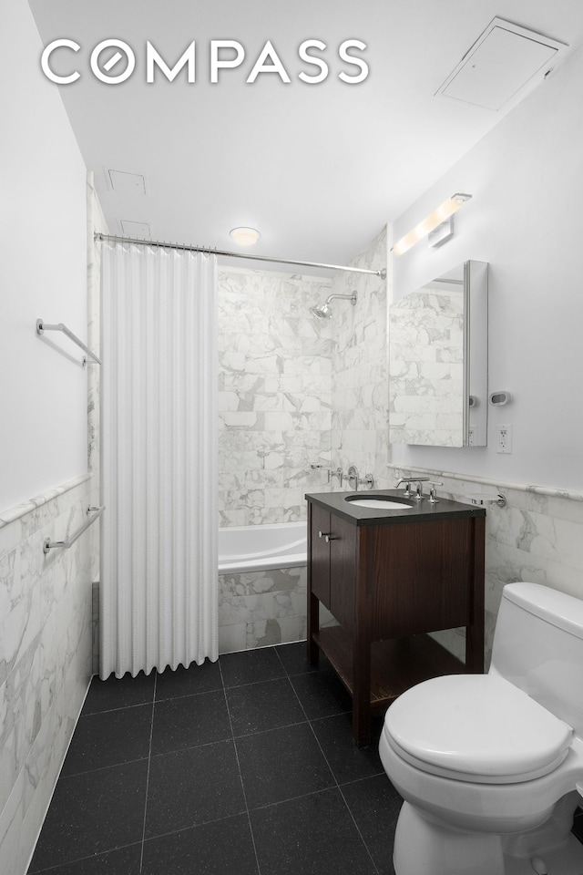 bathroom featuring tile walls, toilet, wainscoting, and tiled shower / bath combo