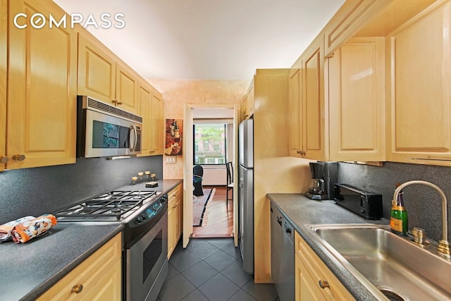 309 E 49th St Unit 2B3B, New York City, NY 10017 - kitchen featuring appliances with stainless steel finishes, light brown cabinetry, dark tile patterned flooring, a sink, and dark countertops