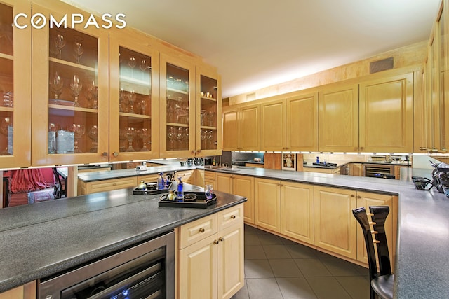 309 E 49th St Unit 2B3B, New York City, NY 10017 - kitchen with beverage cooler, dark tile patterned flooring, light brown cabinets, glass insert cabinets, and dark countertops