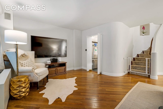 living area with stairs, visible vents, baseboards, and hardwood / wood-style flooring