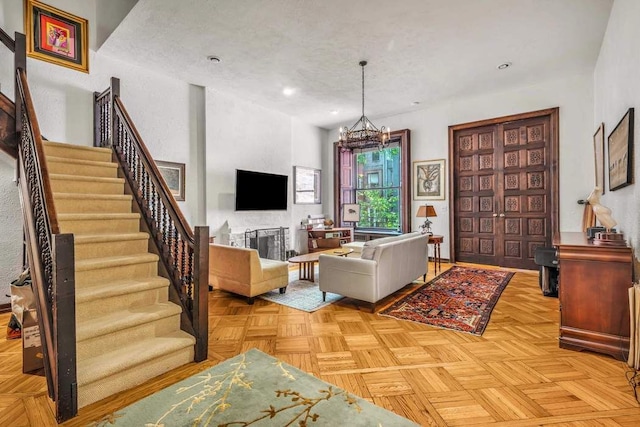 living area featuring a textured ceiling, recessed lighting, a fireplace, stairs, and an inviting chandelier