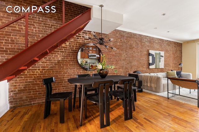 dining area featuring hardwood / wood-style floors and brick wall