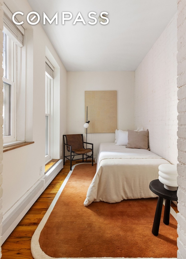 bedroom with a baseboard radiator and wood finished floors