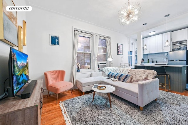 living area with visible vents, cooling unit, a chandelier, and light wood-style flooring