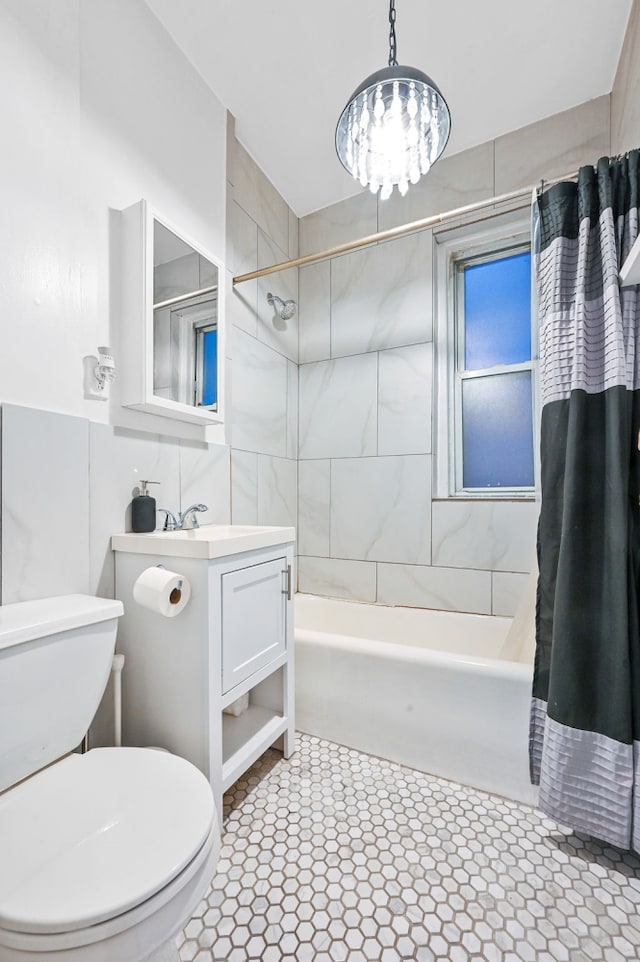 full bath with an inviting chandelier, vanity, toilet, and shower / bath combo with shower curtain