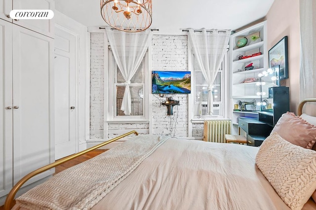 223 E 50th St Unit 2D, New York City, NY 10022 - bedroom featuring radiator, wood finished floors, visible vents, cooling unit, and a chandelier