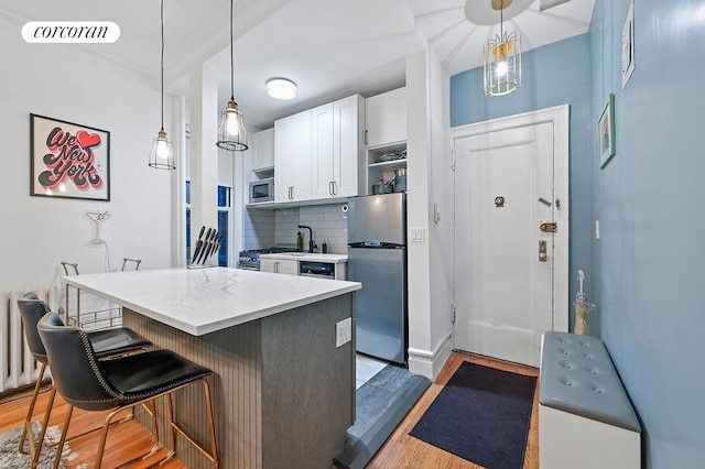 kitchen with tasteful backsplash, visible vents, white cabinets, stainless steel appliances, and light wood-style floors