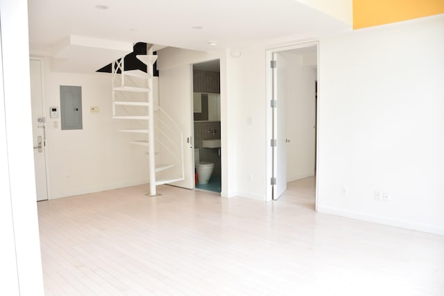 spare room with light wood-style flooring, electric panel, and baseboards